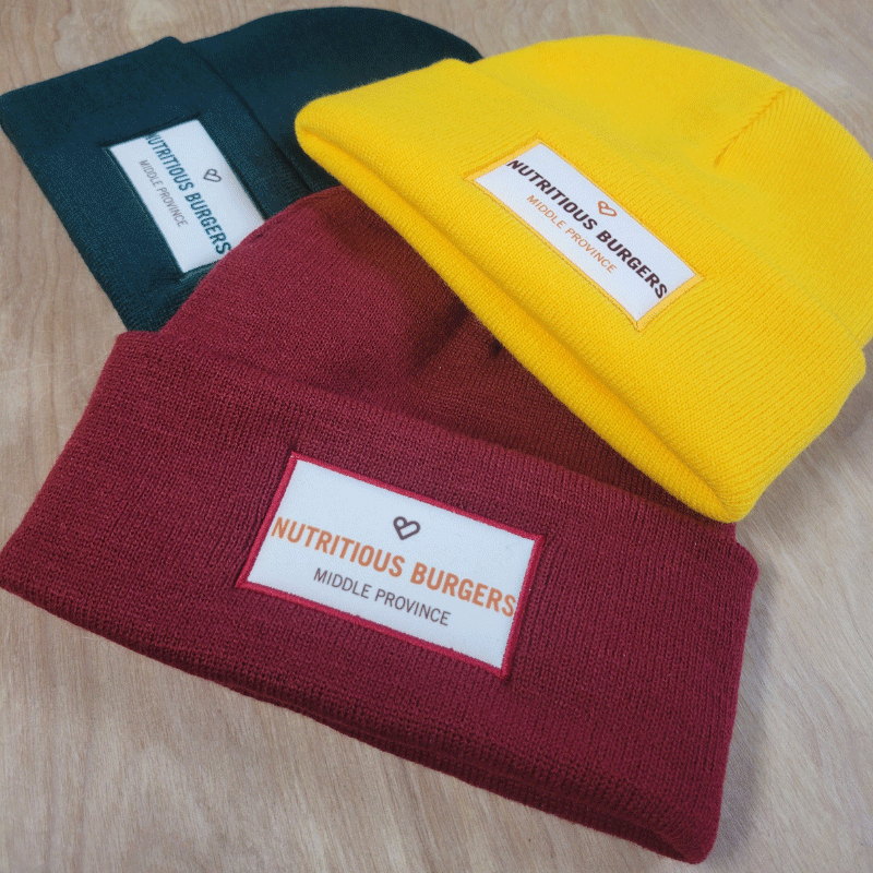Green, red and yellow nutritious burgers middle province toques on wood background.
